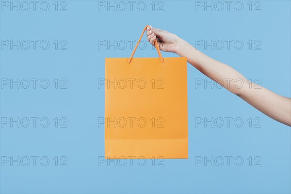 Hand holding shopping bag plain background