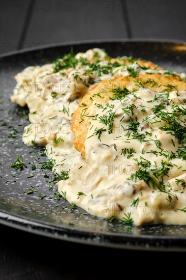 Closeup view of potato patty with fried boletus and creamy sauce on a plate