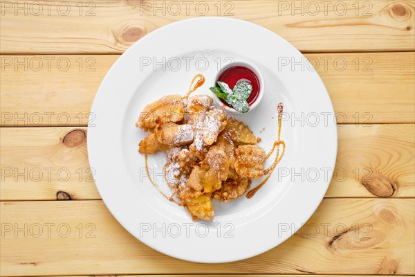 Top view of plate with deep fried fruits in breading served with caramel and strawberry jam