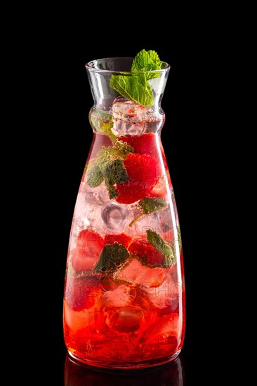 Pitcher with strawberry and mint ice lemonade isolated on black background