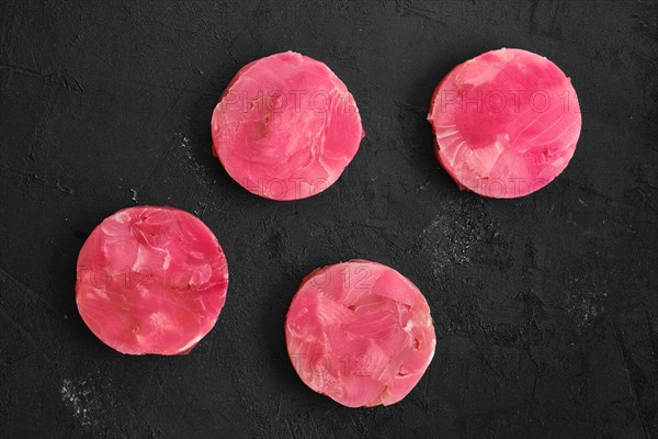 Fresh raw round tuna cutlet on wooden background