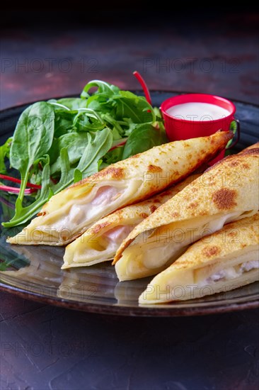 Thin pancakes stuffed with ham and melted cheese served with spinach