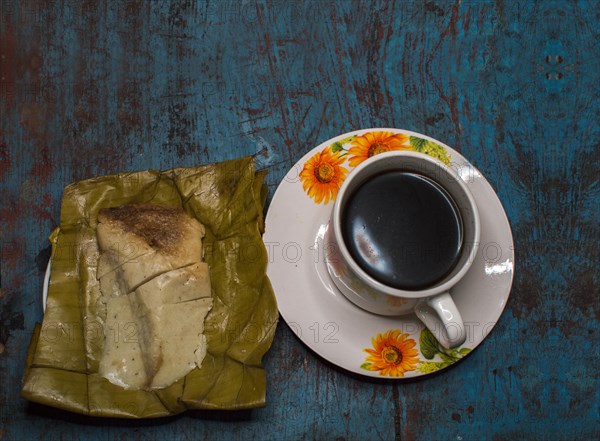 Stuffed tamale with cup of coffee served on wooden table