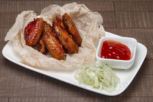 Closeup view of fried chicken wings with ketchup in wrapping paper