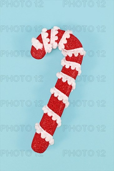 Cute red and white candy cane Christmas ornament on blue background