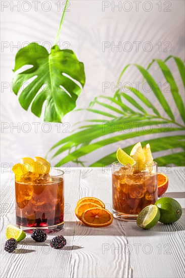 Espresso-tonic refreshing drink with different fruits and syrups on wooden table under morning sun