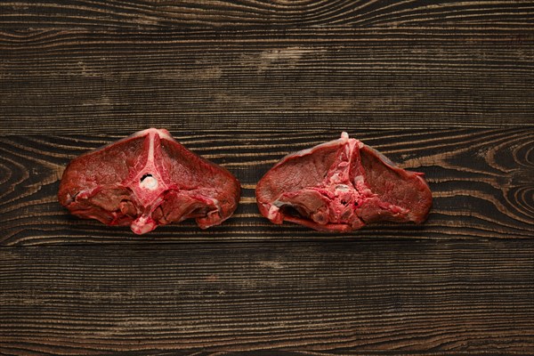 Overhead view of raw fresh deer backstrap over dark wooden background