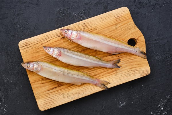 Top view of raw fresh smelt fish on wooden cutting board