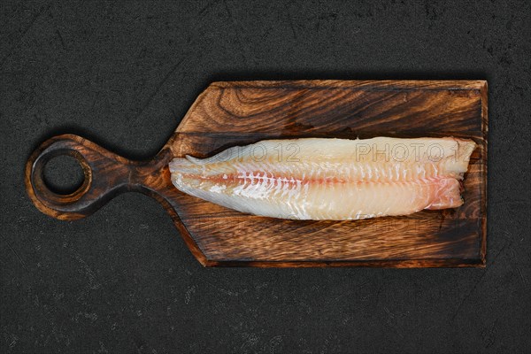 Freshly frozen zander fillet on wooden cutting board