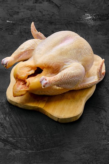 Fresh raw whole farm chicken on wooden cutting board