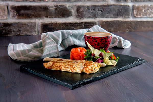 Omelette with salmon on slate plate and cup of latte