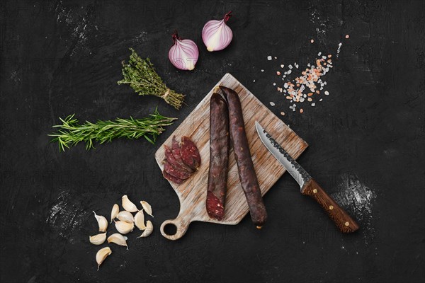 Top view of beef dry aged sausage on wooden cutting board