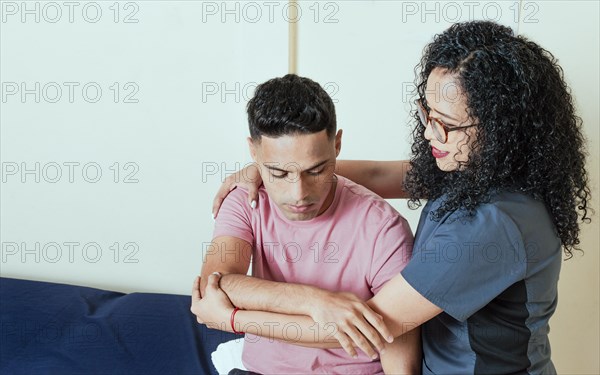 Physiotherapist woman evaluating a patient's arm in the office