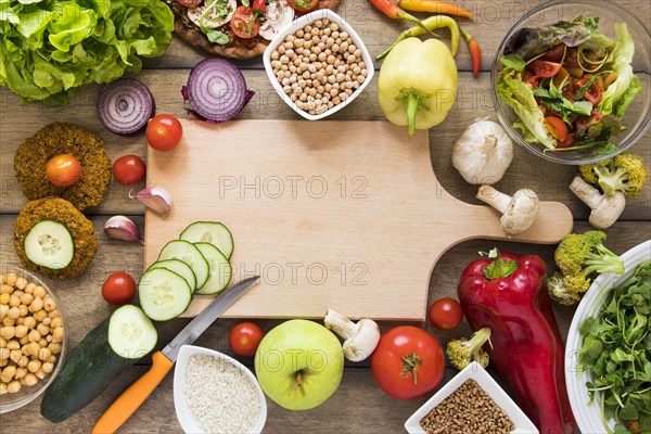 Cutting board surrounded by vegetables