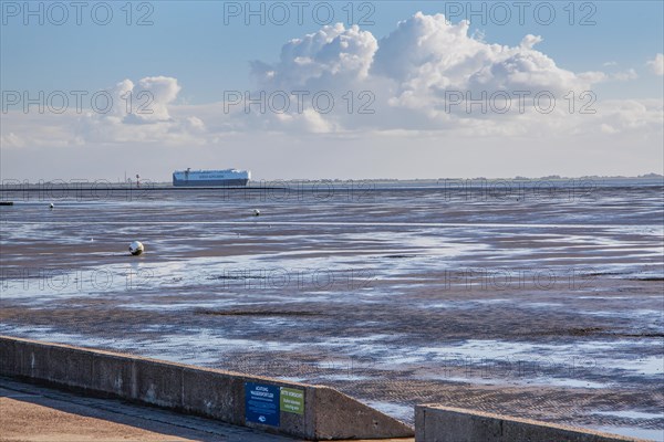 Wadden Sea on the beach promenade with car transport ship in the Weser estuary