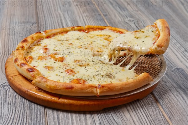 Levitating slice of pizza with cheese on wooden table