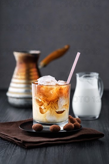 Iced coffee with cream on dark wooden table