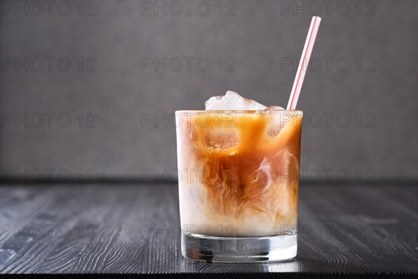 Iced coffee with cream on dark wooden table