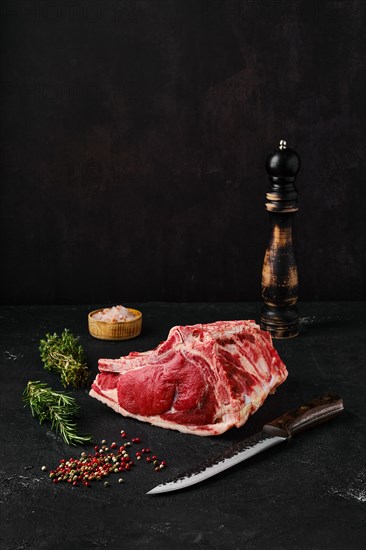 Raw rib-eye steak bone in on dark background