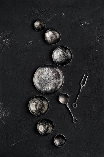 Composition with empty forged bowls of different size on black background