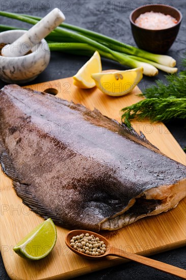 Raw fresh halibut without head on wooden cutting board