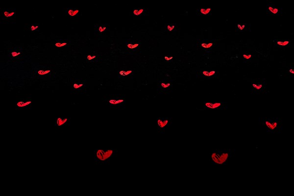 Black fabric background with red hearts shapes