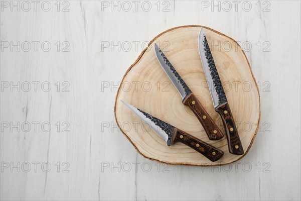 Three forged butchers knives on wooden stump