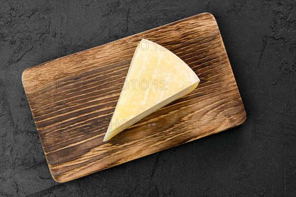 Top view of triangular piece of goat cheese on wooden cutting board