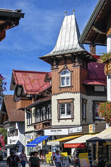 Pedestrian zone with tourists and classic wooden building with wooden shingle facade