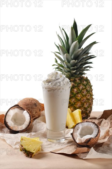 Selective focus composition with coconut cocktail served with pineapple and coconuts on rough paper over the wooden table