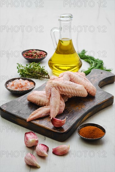 Fresh uncooked chicken wings on wooden cutting board ready for cooking