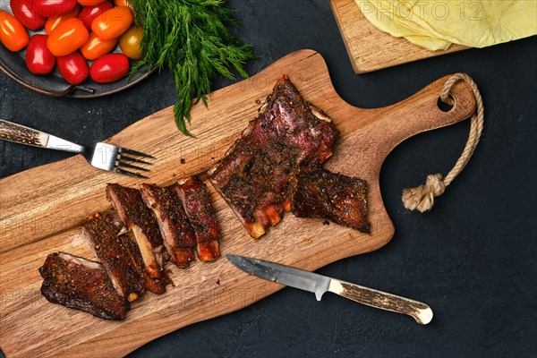 Top view of grilled lamb breast ribs on wooden cutting board