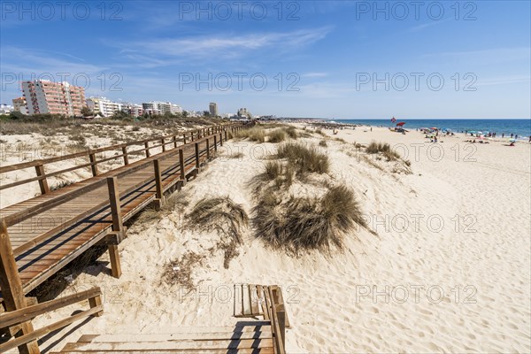 Wide sandy beach with wooden bridges along the dunes in Monte Gordo
