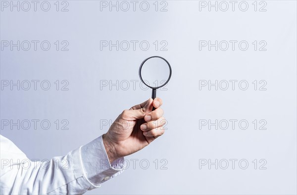 Man hand holding magnifying glass on white background. Hand holding magnifying glass looking for something with space for text
