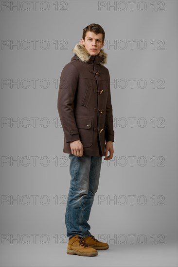 Full length portrait of handsome man in warm woolen coat posing in studio