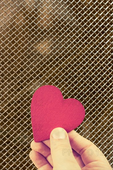 Red heart shaped object in hand as love concept