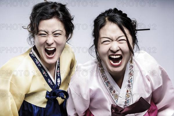 Portrait of two woman in Korean traditional costume with open mouths