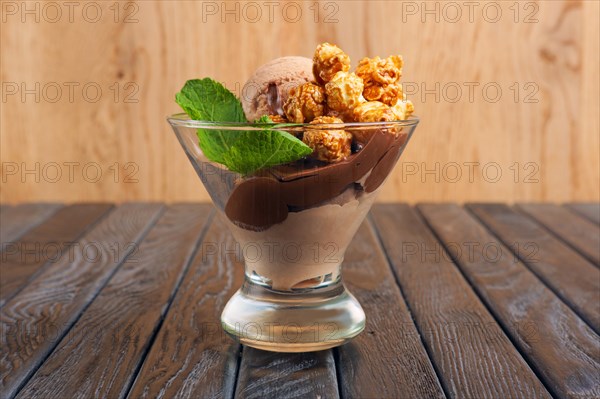 A cup of chocolate ice cream decorated with caramel popcorn and mint leaves
