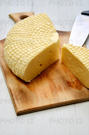 Fresh Adyghe cheese cut on slices on wooden cutting board
