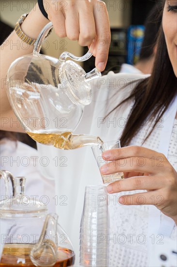 Herbal tea brewed in glass teapot and tea plant in a bottle