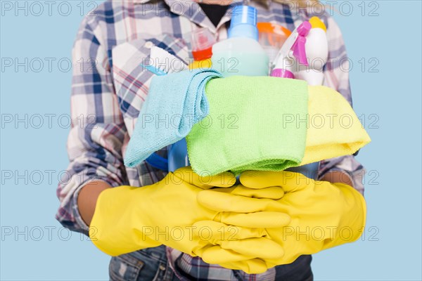 Mid section cleaner holding bucket with cleaning products wearing yellow gloves