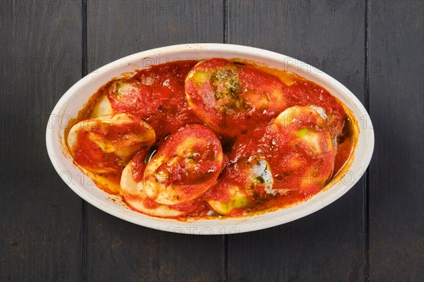 Overhead view of lamb dumplings with spicy tomato sauce baked in oven