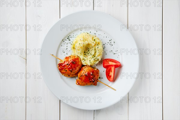 Top view of roasted chicken fillet on skewer with barbecue sauce and mashed potato on white wooden table