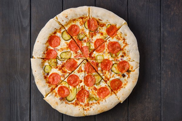 Top view of pizza pepperoni with cheese crust on dark wooden table