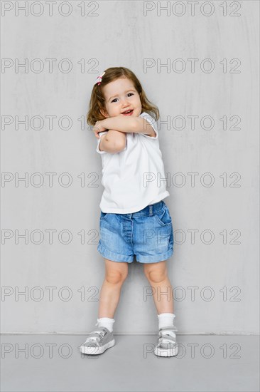 Two years old girl in white t-short and jeans shorts posing in studio