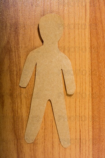Man shape cut out of paper on wooden texture