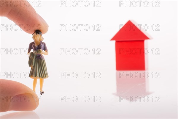 Woman figure nearby a house made of color blocks on a white background