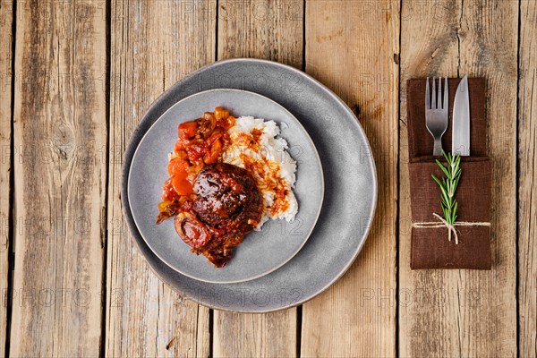 Overhead view of plate with ossobuco on wooden table