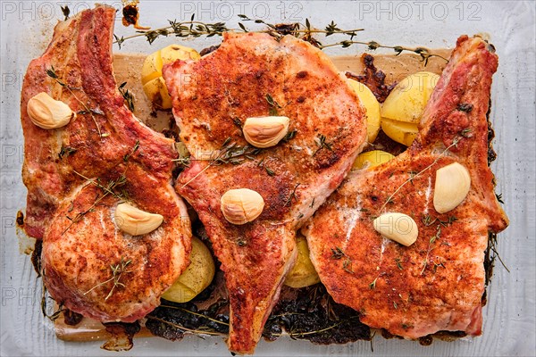 Steak with bone and potato baked in oven in a roasting pan with garlic and thyme