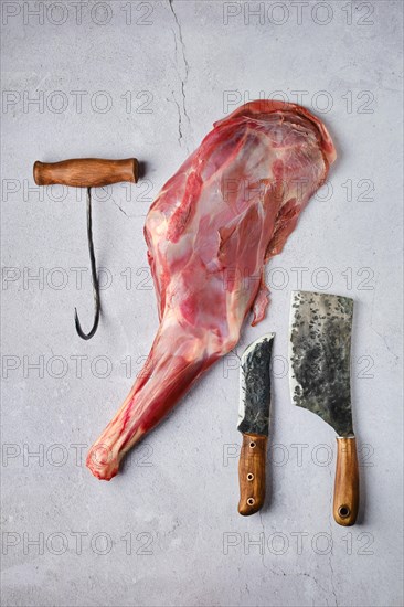 Overhead view of raw fresh deer leg with spice and herb over concrete background